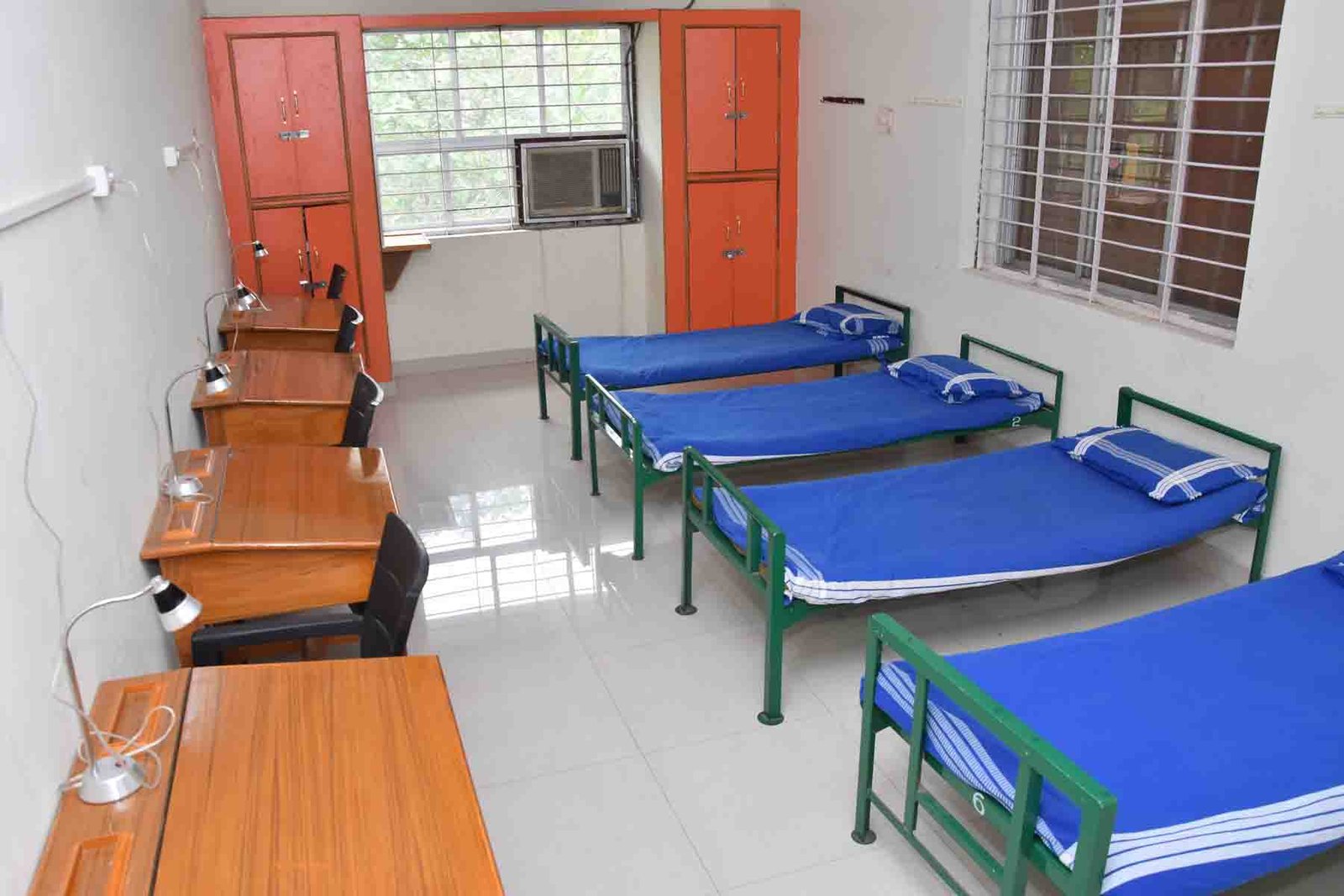 Hostel room with four beds, desks and wardrobes